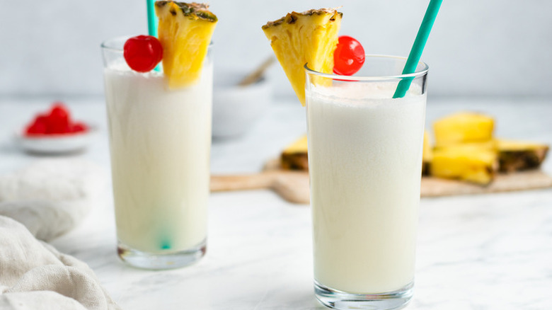 Tall glasses with white, creamy drink garnished with pineapple.