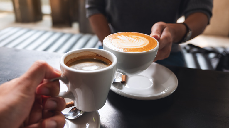 Two hands holding coffee mugs