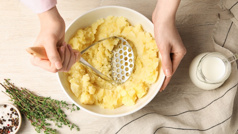 person mashing potatoes