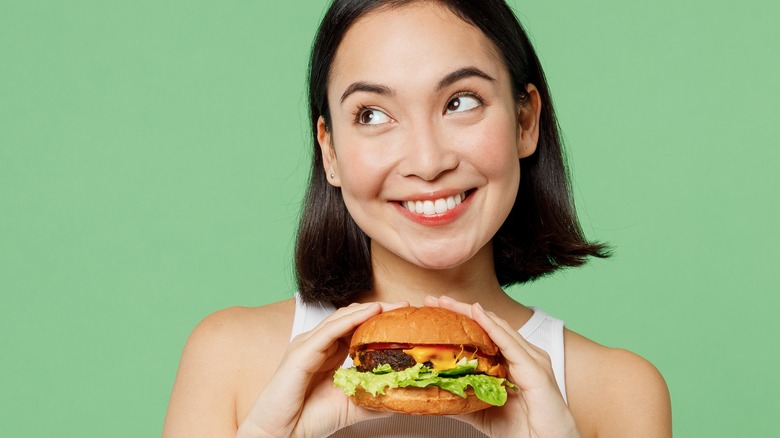 woman smiling holding fast food burger