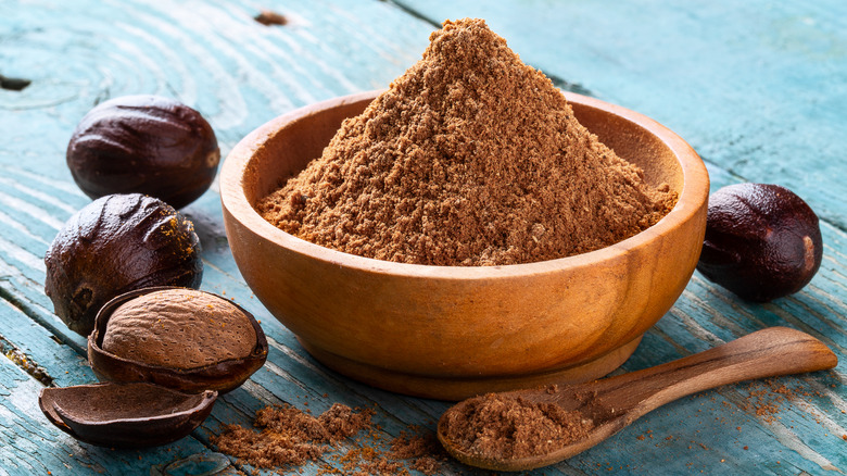 whole nutmeg in shell and ground nutmeg in bowl and spoon