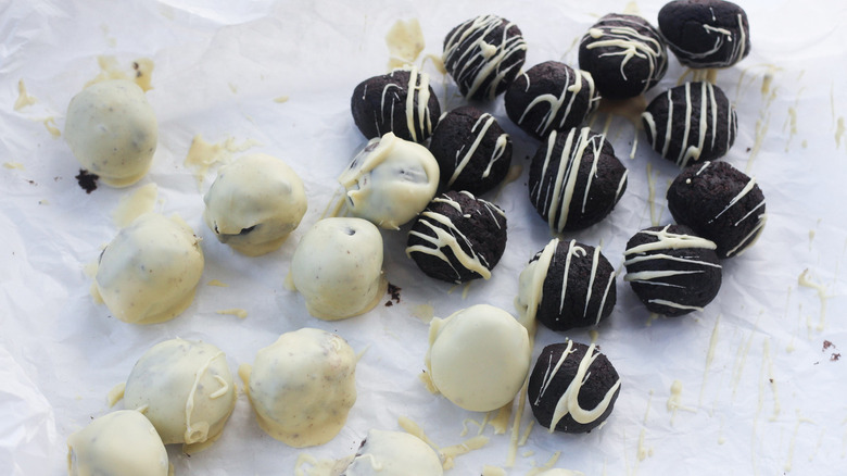 Fully coated Oreo truffles next to Oreo truffles drizzled with white chocolate