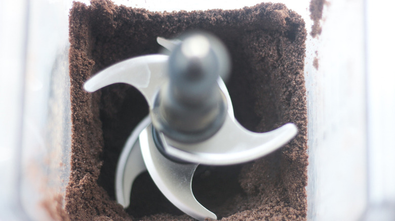 Close up of food processor blades surrounded by ground up Oreos