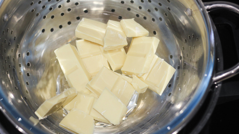 A silver colander filled with pieces of white chocolate 