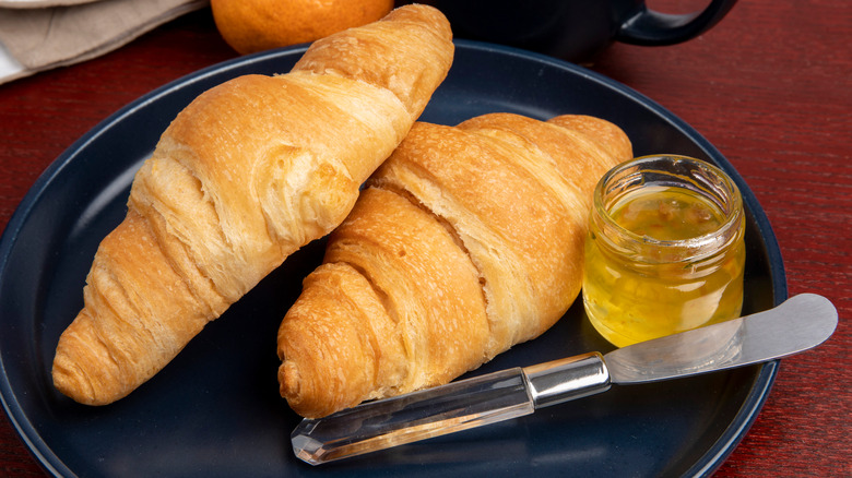 two crescent rolls on a plate with preserve