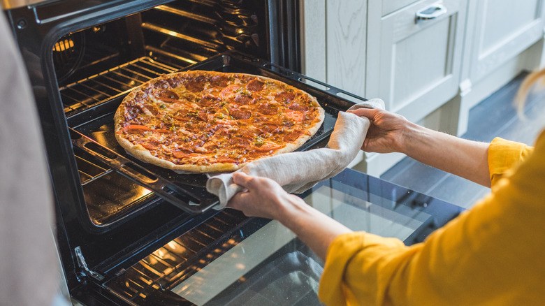 woman taking pizza out of oven