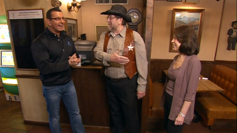 Robert Irvine with a man dressed like a cowboy, and his wife