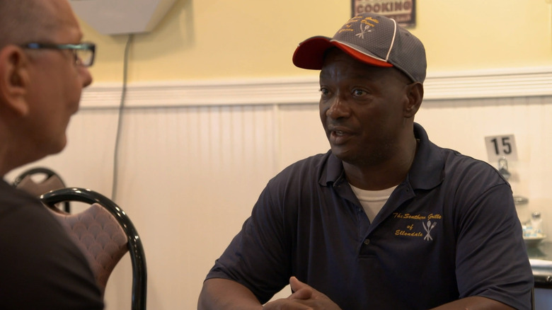 Two men sitting at a table talking with serious expressions