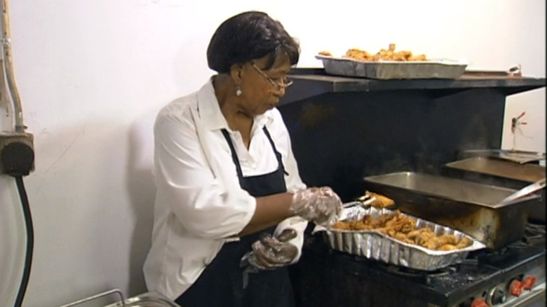 Woman serving fried food out of a foil pan