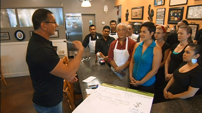 Robert Irvine speaking to a group of people in a restaurant