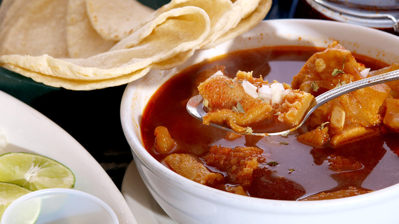 spooning from bowl of menudo