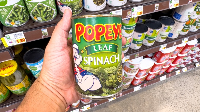 hand holding can of spinach in grocery store