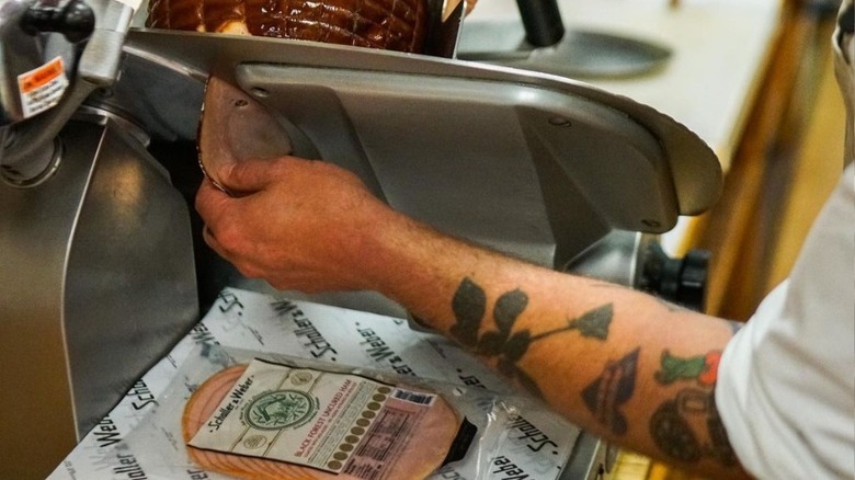 man slicing ham at deli