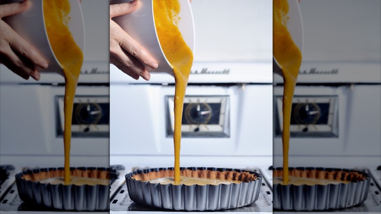 Pouring pumpkin pie mix into shell