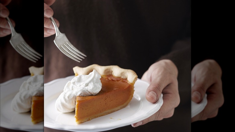 Person eating pumpkin pie slice