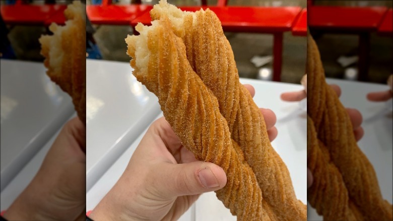 Hand holding two Costco churros