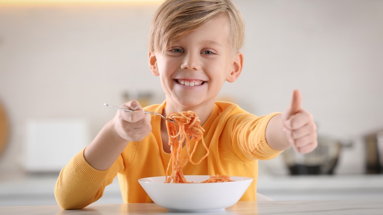 boy eating spaghetti and giving a thumbs up