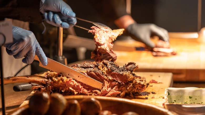 Brisket being chopped in a kitchen prep area