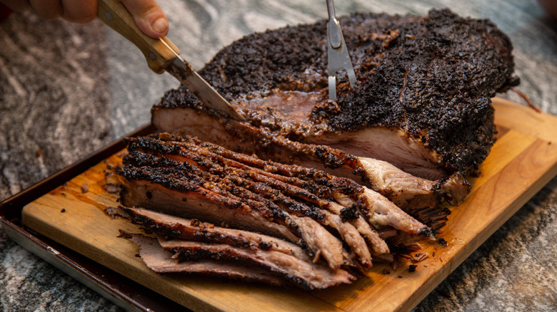 Smoked brisket being sliced on a cutting board