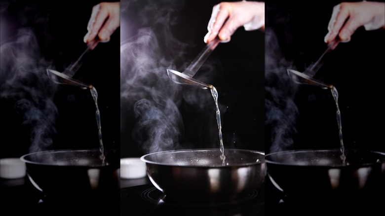 Person adding broth to risotto