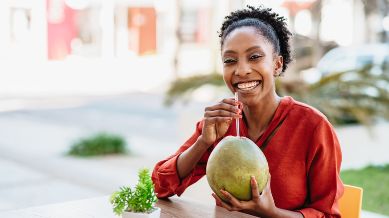 Woman drinking from coconut with straw