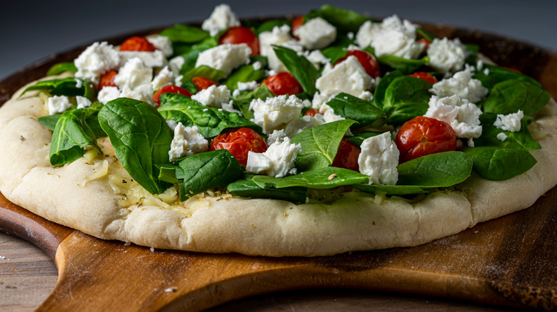 uncooked pizza on wooden peel