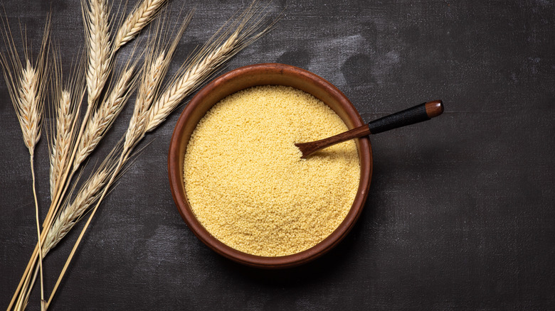 semolina flour in a rustic wooden bowl with wheat stalks