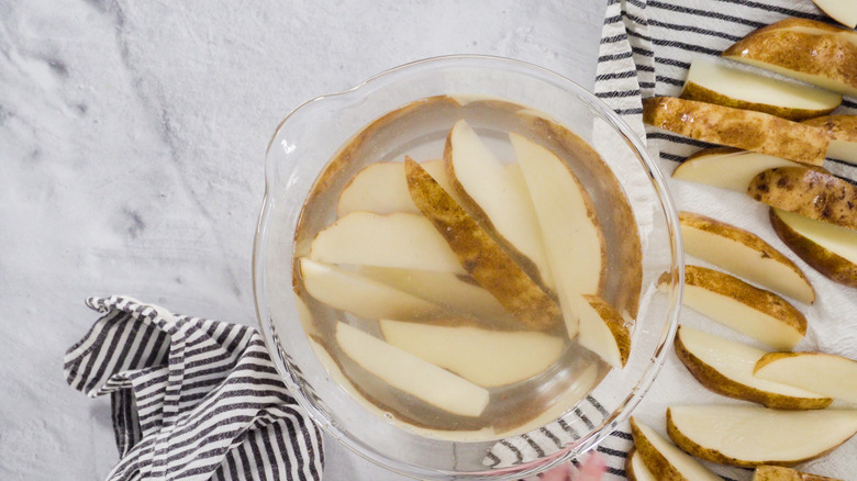 Potato wedges in a bowl of starchy water