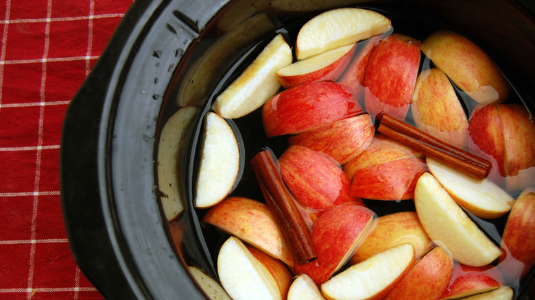 crockpot with sliced apples, cider, and cinnamon