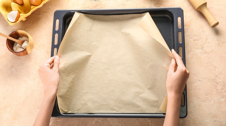 woman putting parchment paper on baking sheet