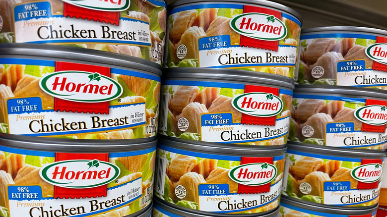 Cans of Hormel chicken stacked on grocery store shelf