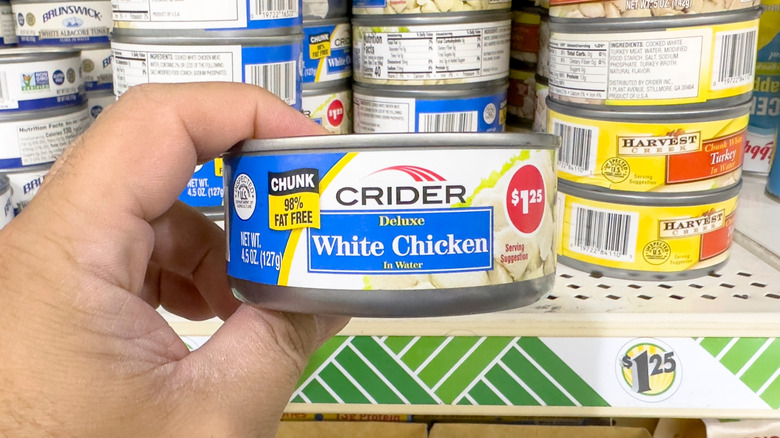 Hand holding can of Crider white chicken in Dollar Tree