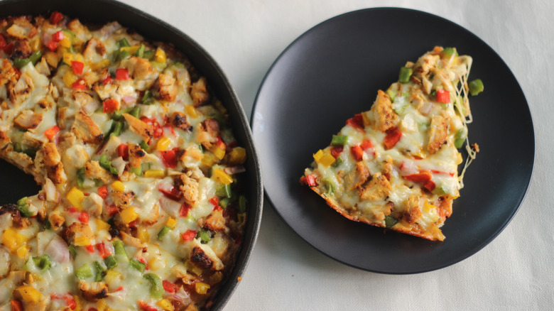 Homemade chicken pizza with slice on black plate