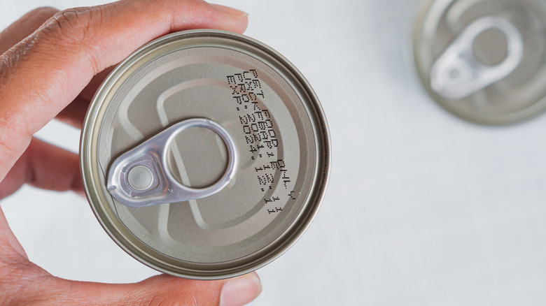 Person holding pull tab can displaying best-by date