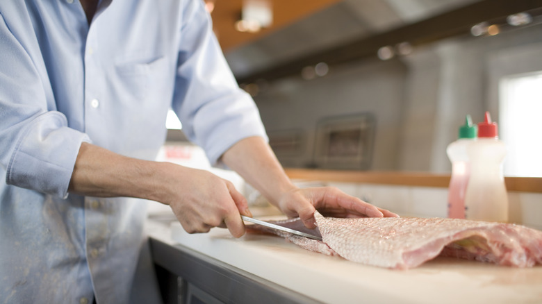 person fileting fish on counter