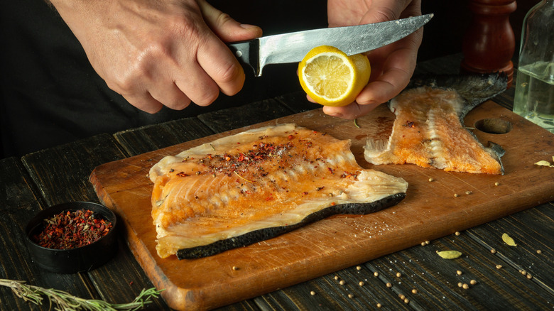 person cutting lemon onto fish