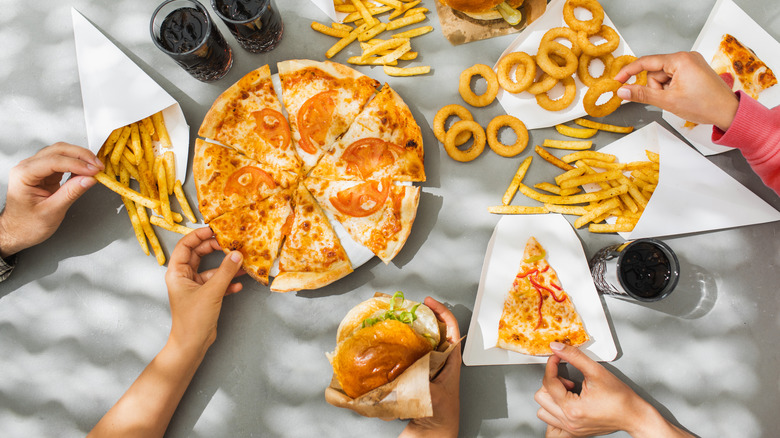 Hands grabbing fast food at a table