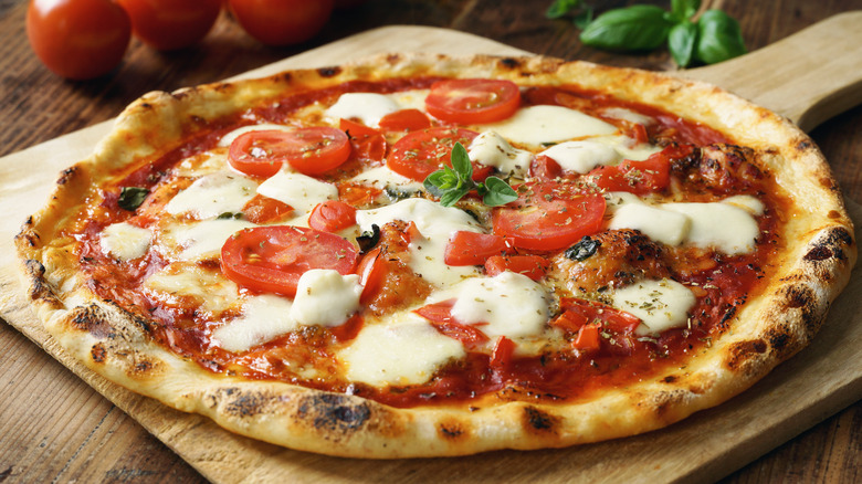 unsliced pizza on wooden board