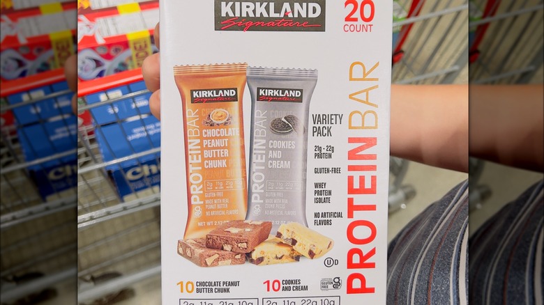 Person holding a box of Kirkland protein bars