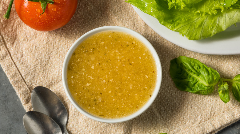 Italian dressing on table next to salad ingredients