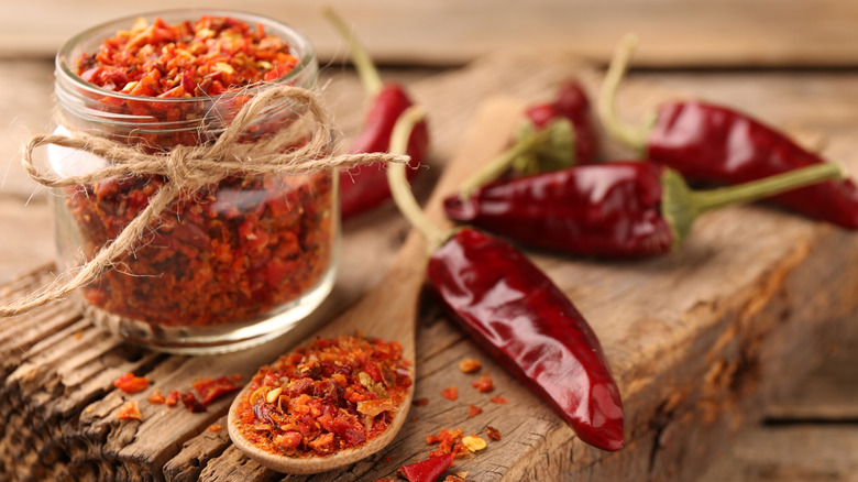 Red pepper flakes and chili peppers with wooden spoon