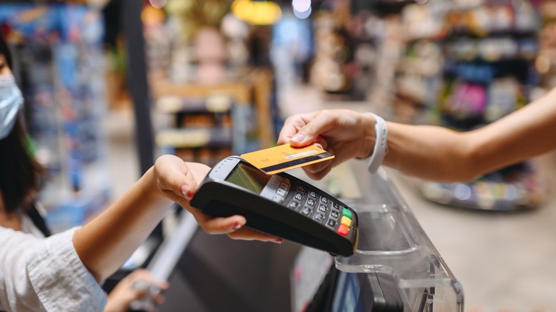 person touching credit card to reader