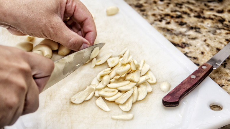 hands chopping garlic on cutting board