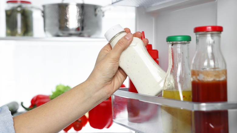 person grabbing sauce out of refrigerator