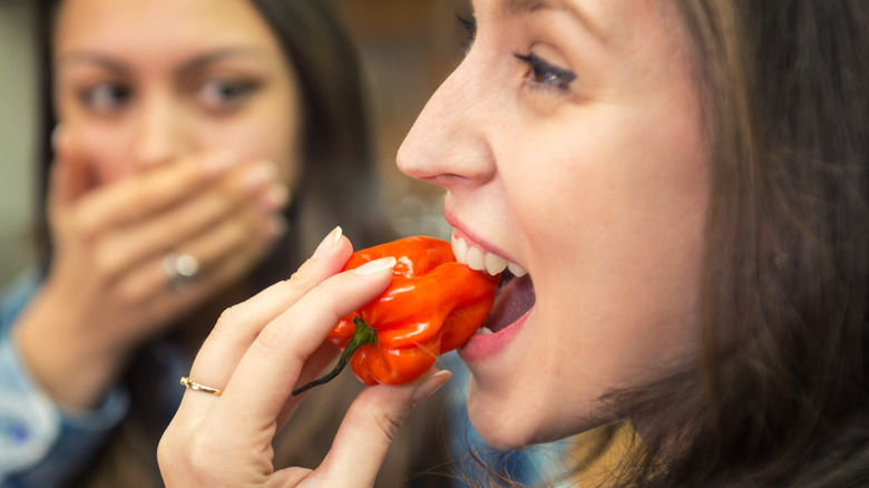 girl biting into chili pepper