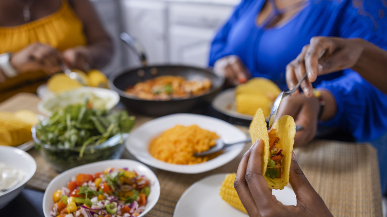 hands holding taco shell and filling it