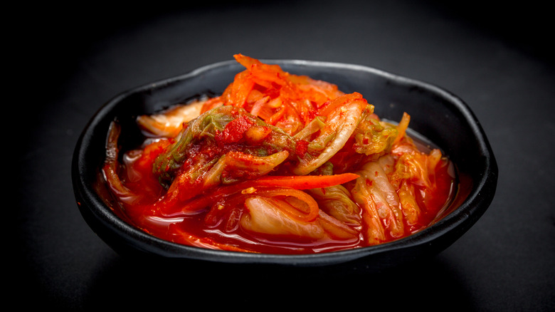 a black bowl full of kimchi on a black background