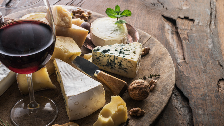 blue, swiss, goat cheese and wine with nuts on a cheese board