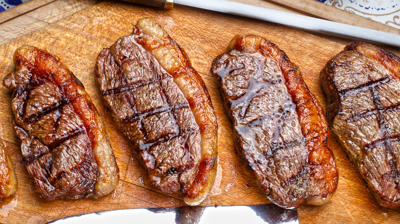 Four fatty steaks on a cutting board