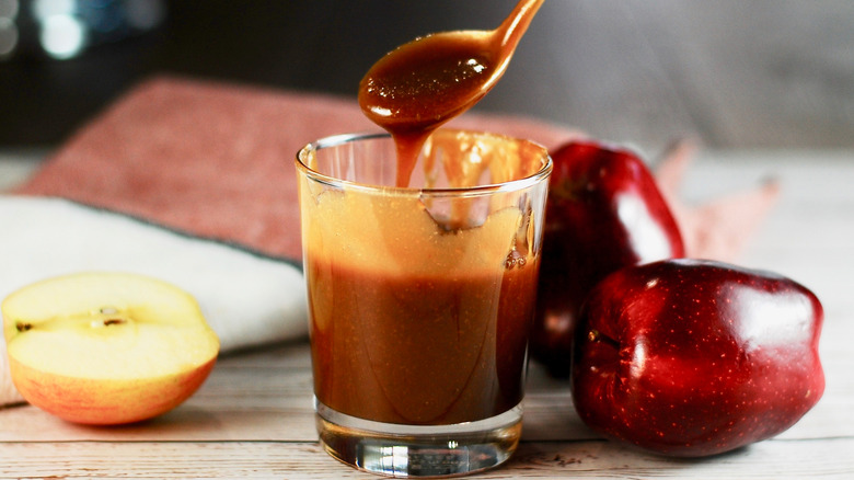 Caramel sauce dripping from spoon next to apples